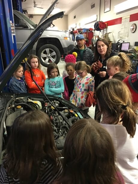 Girlington Garage owner Demeny Pollitt explaining how to check your oil to local girl scout troup